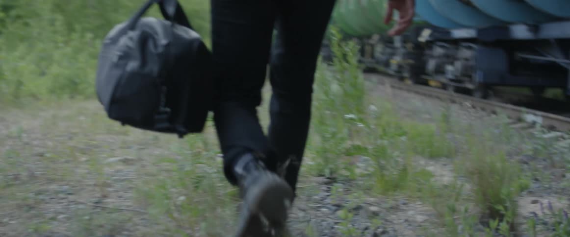 A man carries a duffel bag next to a moving train