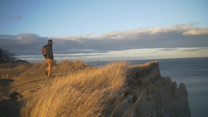 A man approaches the edge of a rocky cliff