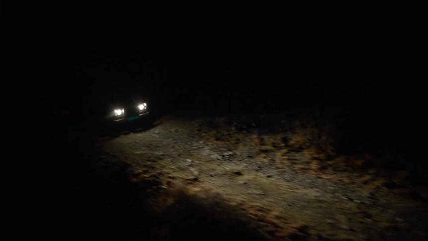A vehicle travels down a gravel road at night