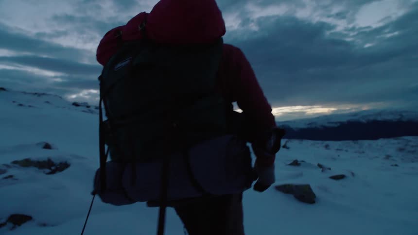 A person is hiking in the snow at sunset