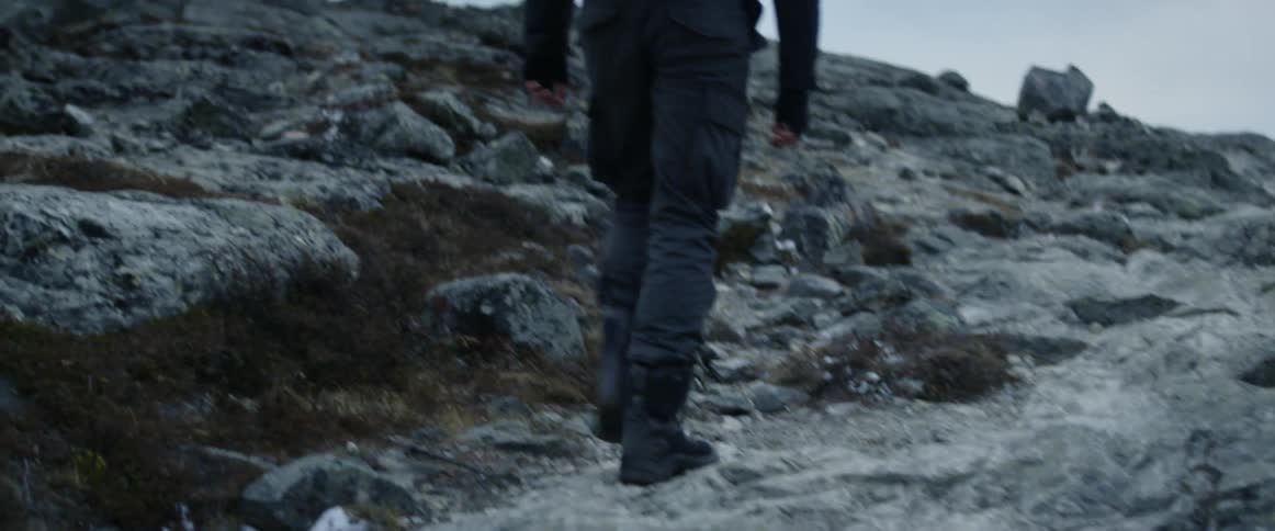 Man wearing backpack is walking up a rocky slope