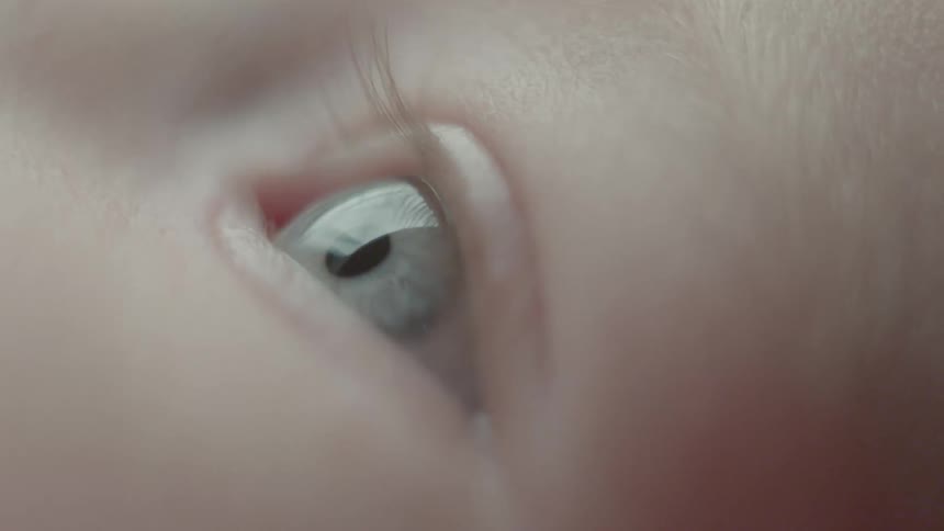 A baby holds its eyes open