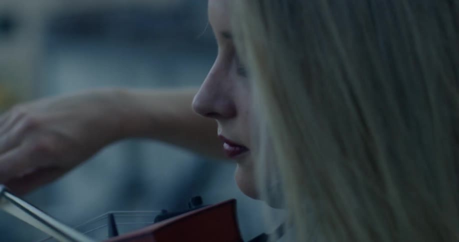 A woman is playing a violin on a windy day