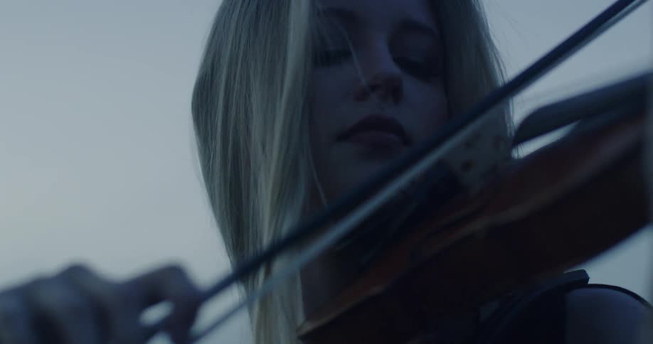 A woman is playing a violin on a cloudy day