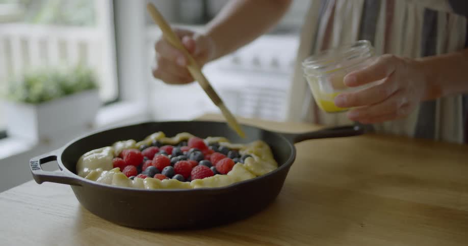 A woman rubs an egg wash on a pie crust