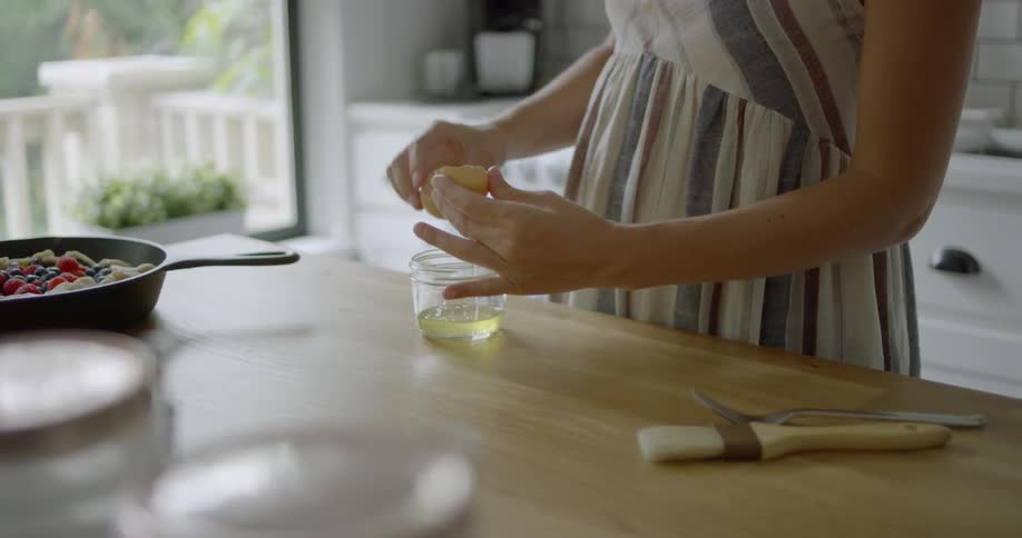 A woman cracks an and separates the yolk from the white