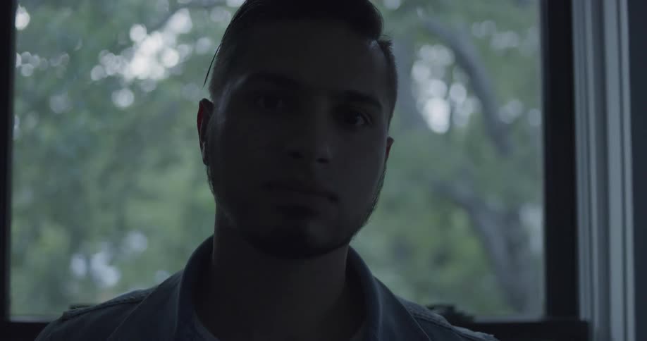 Man inside house in front of window is staring off