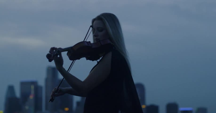A woman plays near the city at sunset