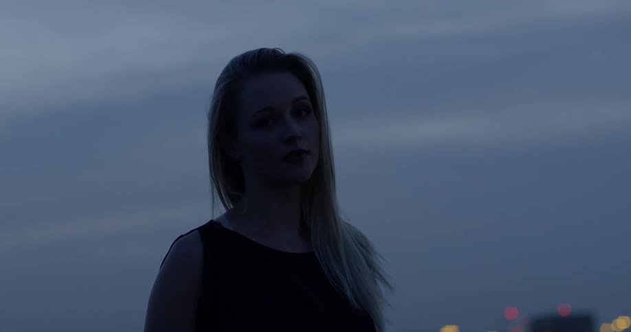 Woman stands with the city night sky behind her