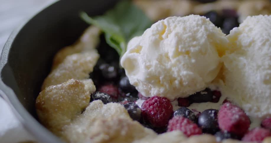 Ice cream melts on top of a berry dessert
