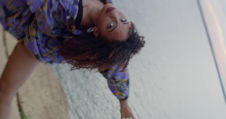 A woman dances abstractly next to a lake
