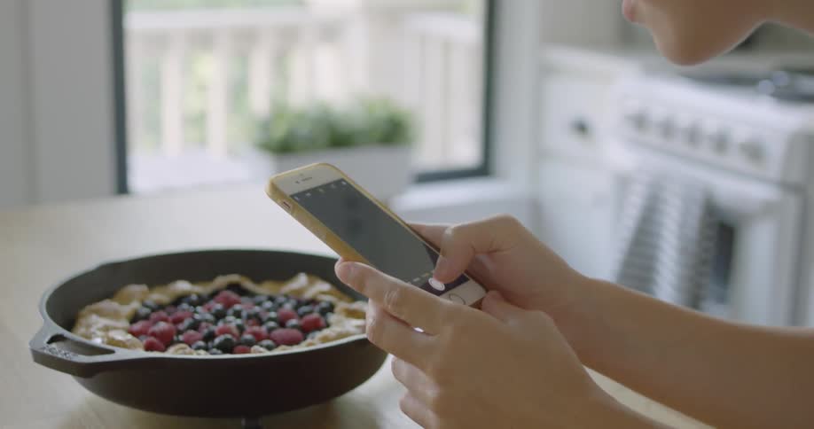 A woman takes a photograph of a pastry dish