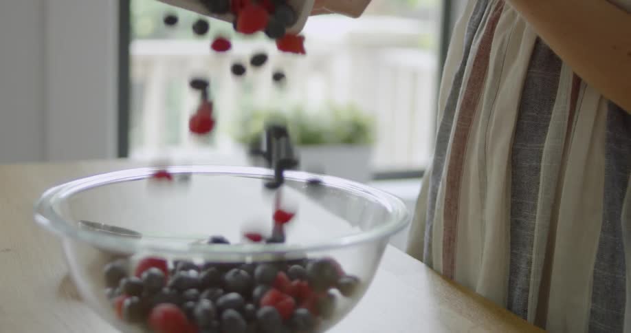 A woman puts berries in a bowl
