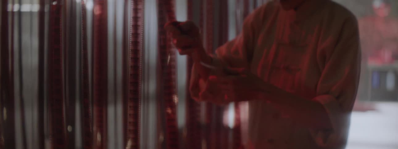 An asian woman inspects hanging film in a dark room