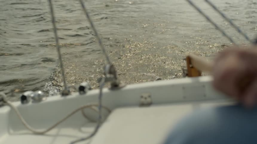 A person steers a boat from the motor