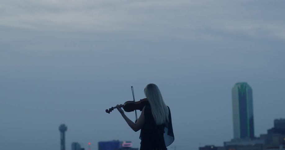 A woman plays violin in a city