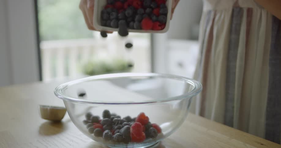 A woman mixes berries in a bowl