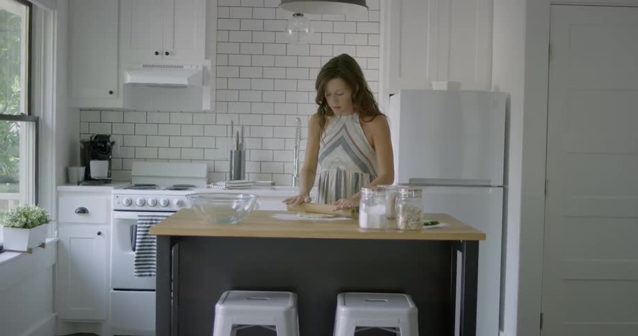 Woman rolls out dough in her kitchen