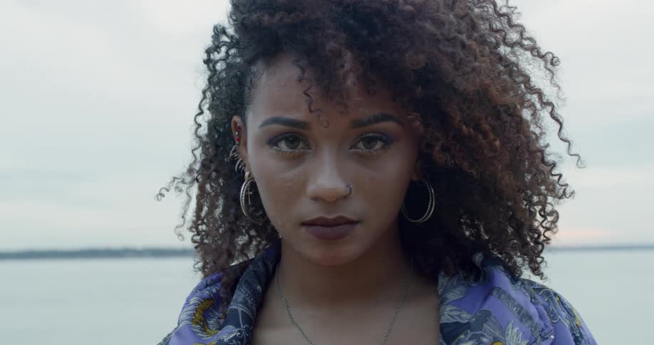 A woman with a pierced nose stands near water