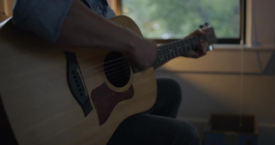 Man sitting in a house is playing the guitar