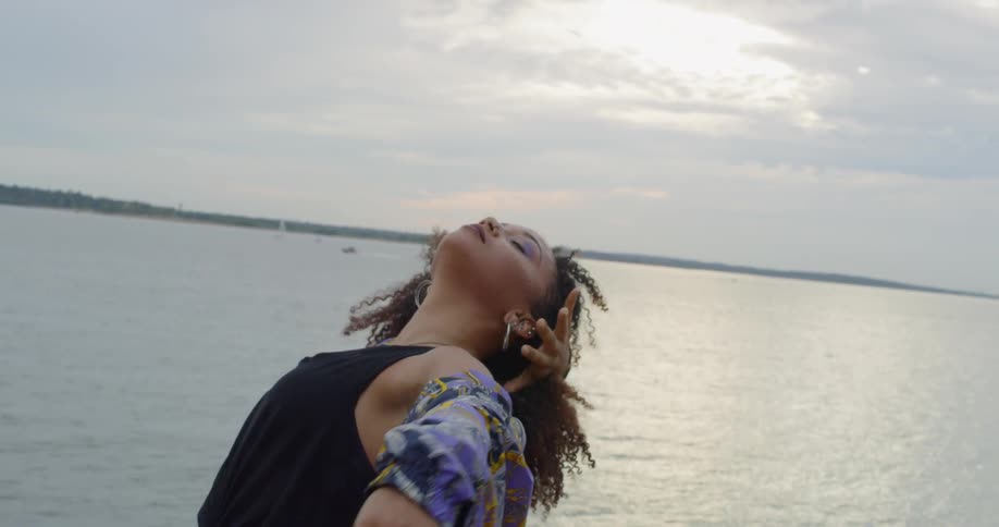 A woman leans back dancing by the water