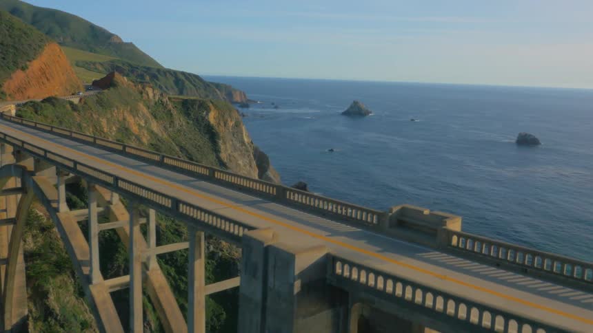 Car traveling over tall bridge on the coast overlooking the ocean
