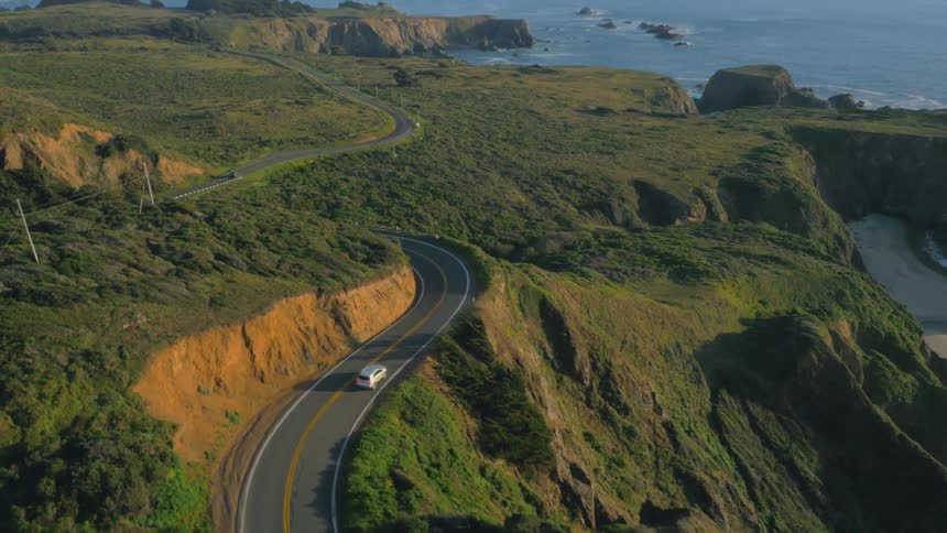 The car drives down the shore side road