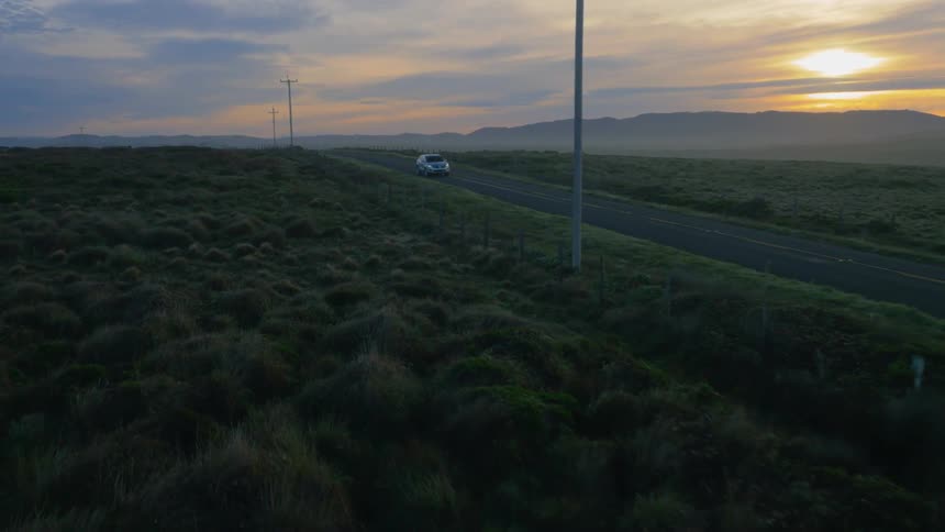 Car drives on a rural road at sunset