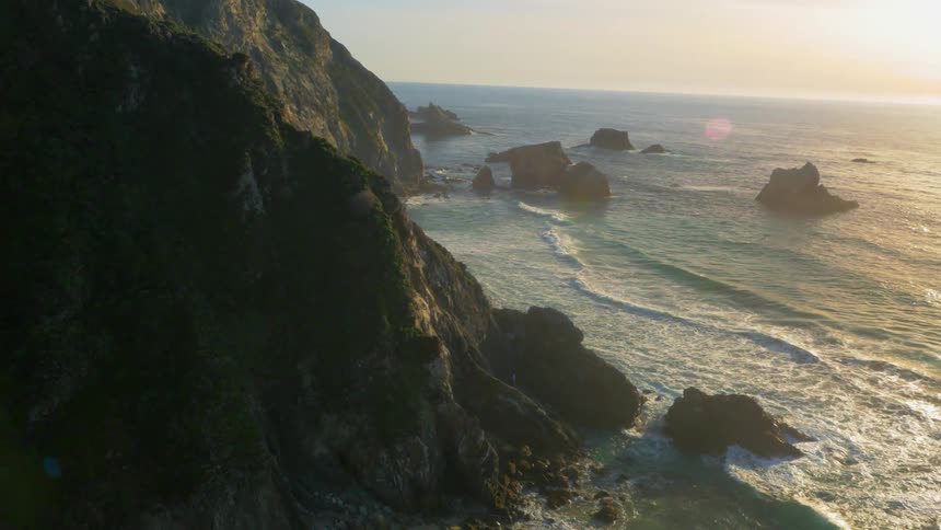 Ocean waves rolling onto rocky beach as sun sets