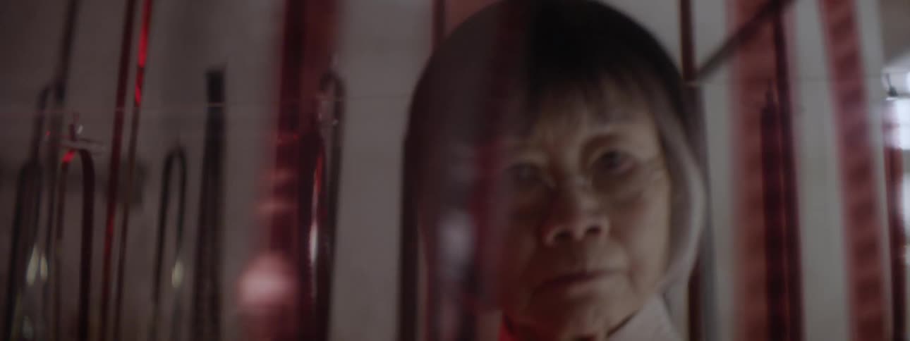 An asian woman walks frantically and stares at hanging film sheets