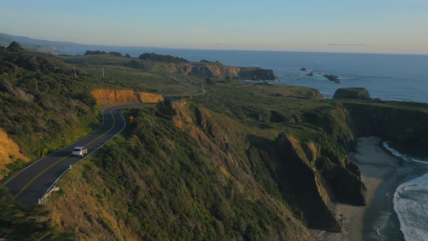 A car drives down a road on the cliff