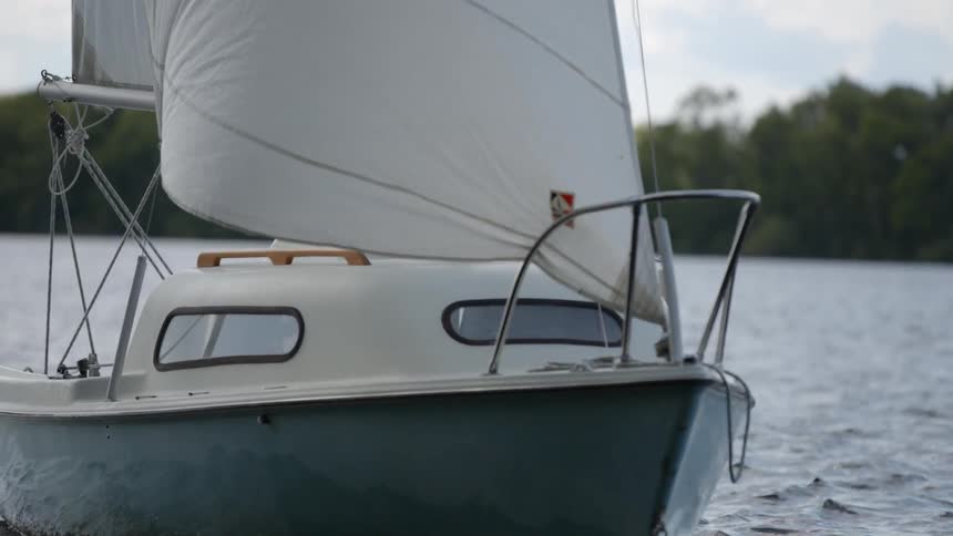 A sailboat being steered by a man makes a turn