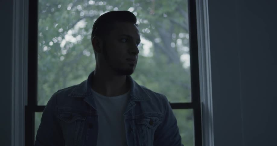 A man stands in front of a window