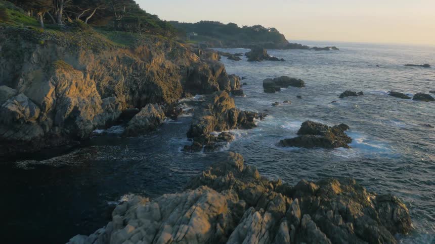 The water crashes against the shore lined with rocks