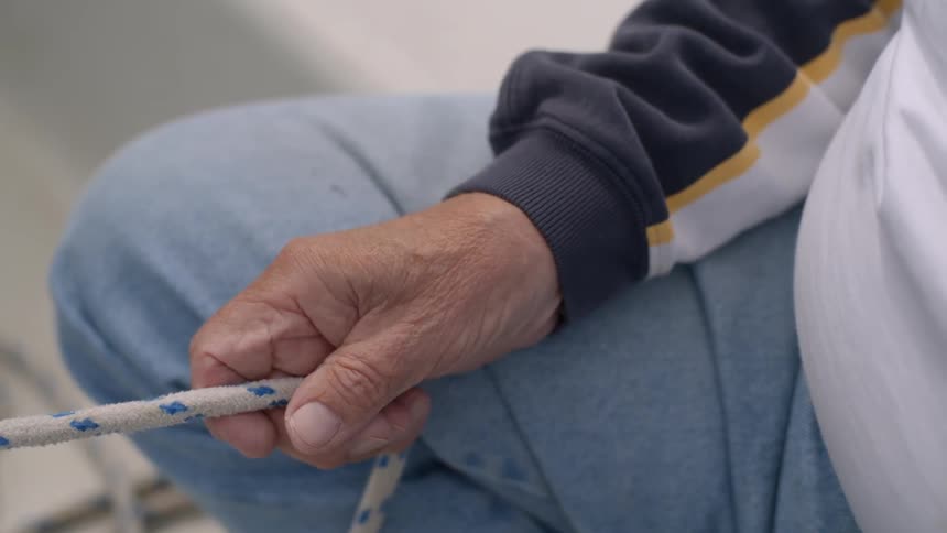 Man sitting while he holds a rope