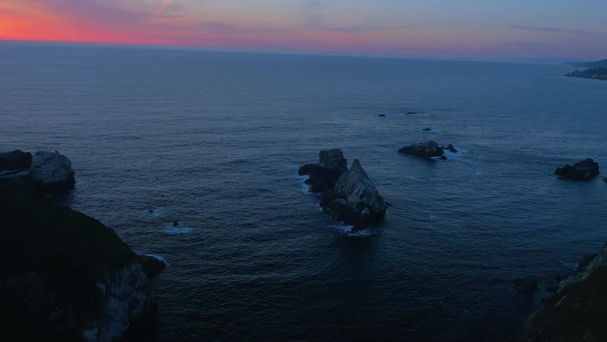 The sun is nearly set near the shore