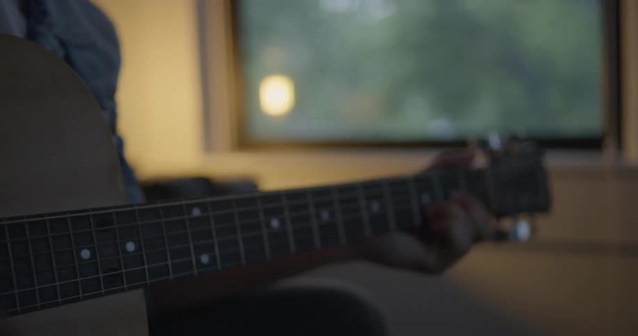 A man grabs an acoustic guitar and sits down to play