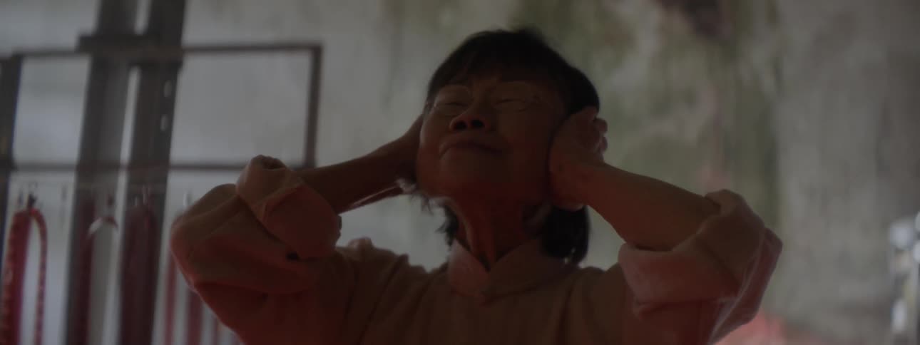A woman covers her ears in the dark room