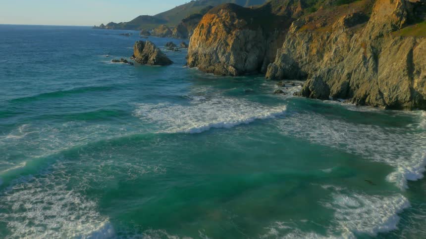 Ocean waves flow towards rocky cliffs