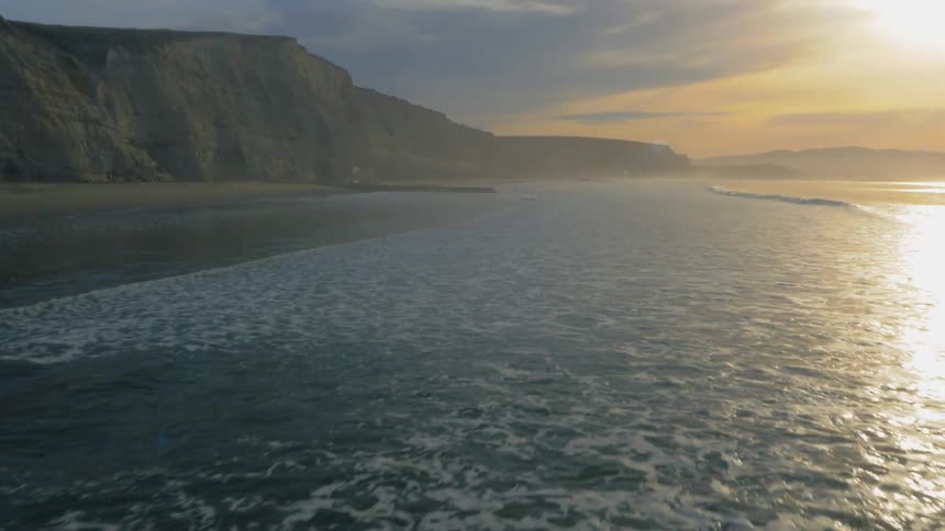 Ocean waves flowing onto beach at sunset