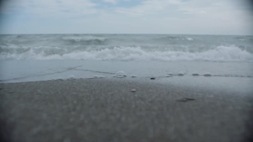 The water slowly moves over the sand on a cloudy day