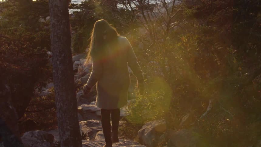 A Woman Hikes Down To The Shore at Sunset