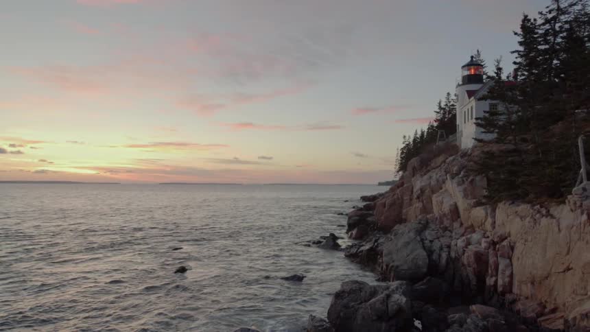 The Sun Sets Off The Coast In Front Of A Lighthouse