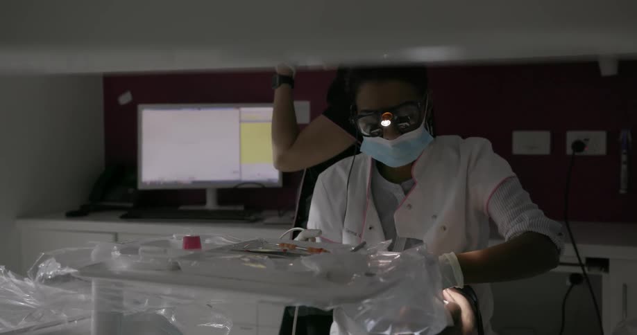 A dentist is working on a patient in the chair