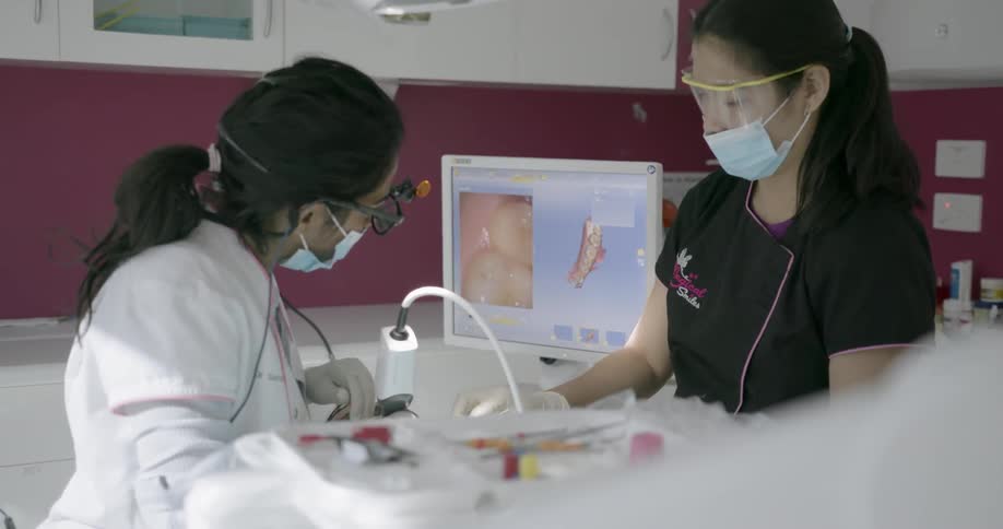 A dentist works with an assistant on a person's teeth
