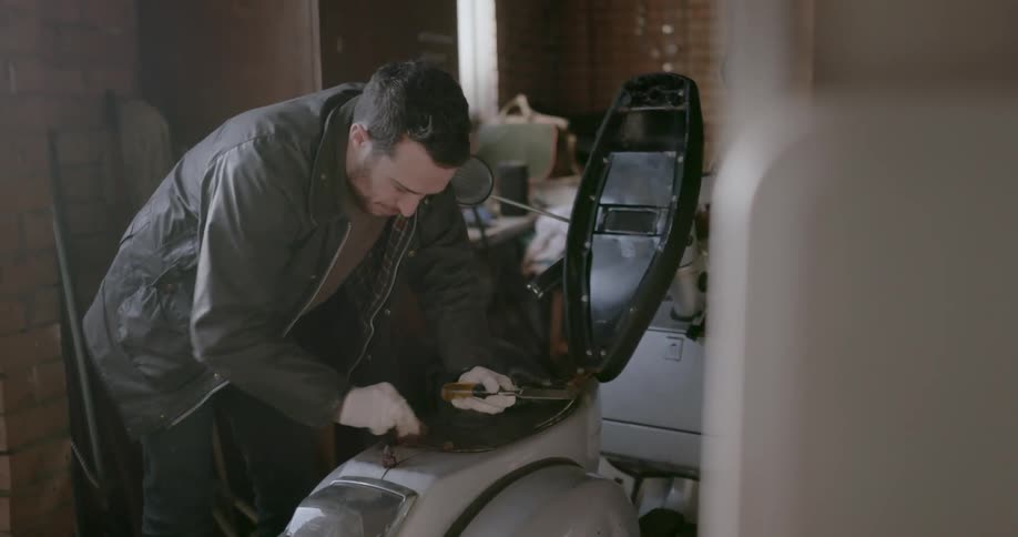 A man works on a moped in a garage