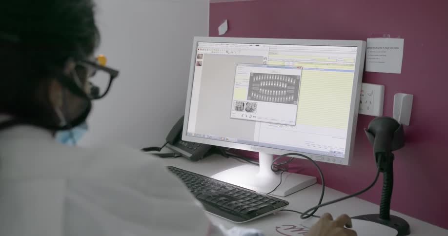 A dentist examines x rays on a computer