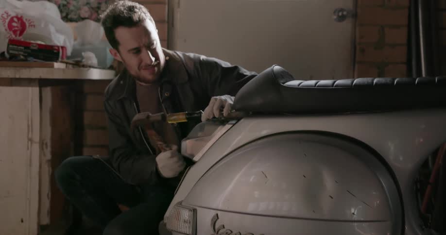 A man works on a scooter seat in a garage