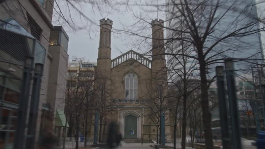 Pedestrians walk on the walkway in front of a church in the city