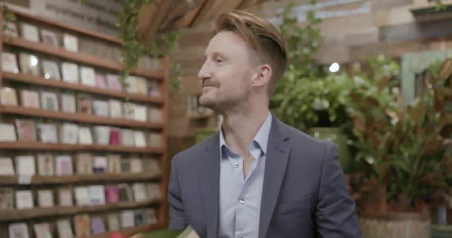 Man wearing suit is picking up a bouquet of flowers at flower shop